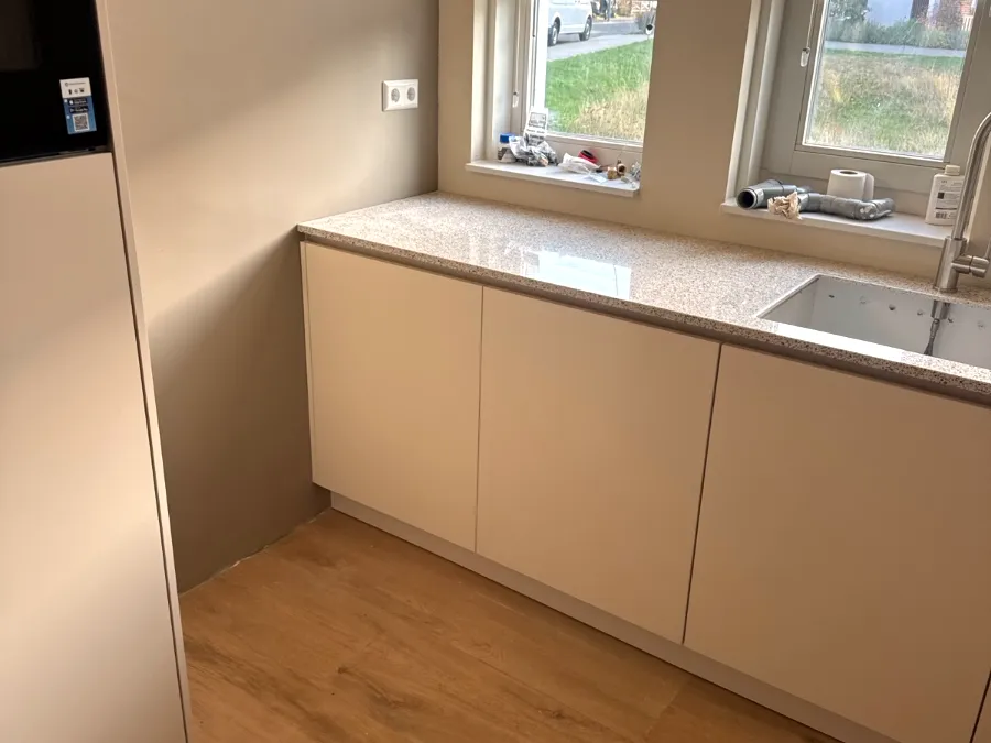 Crèmekleurige greeploze keuken met terrazzo werkblad