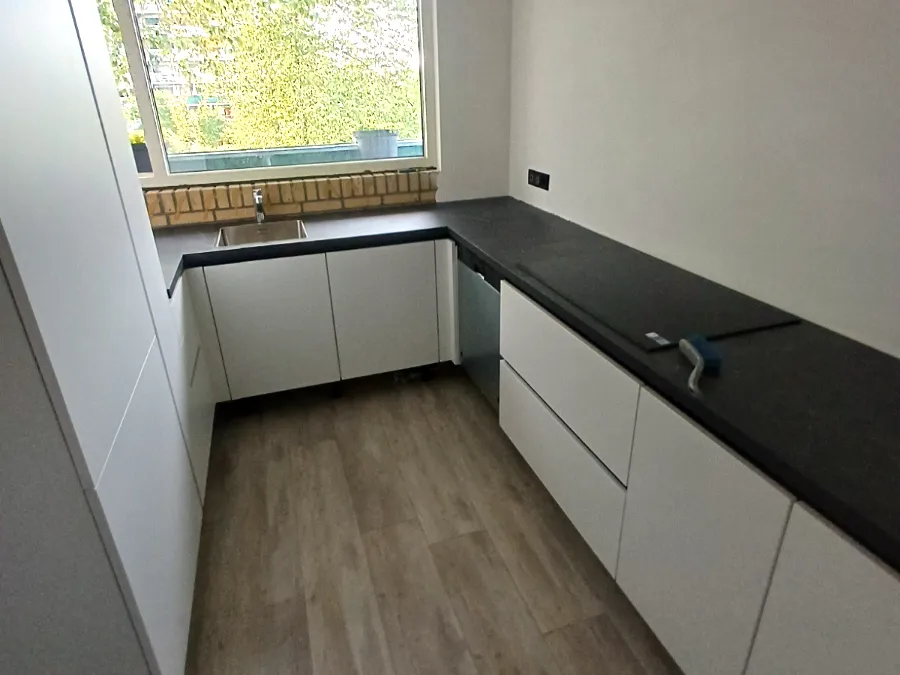 Smalle witte keuken met zwart werkblad