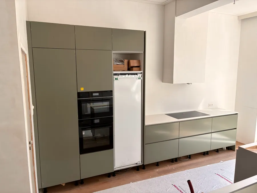 Saliegroene keuken met hoge kastenwand