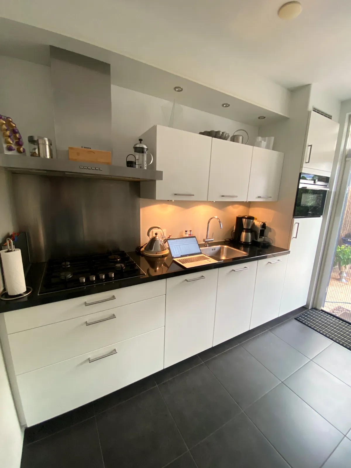 Witte keuken met zwart werkblad en verlichting onder de bovenkasten