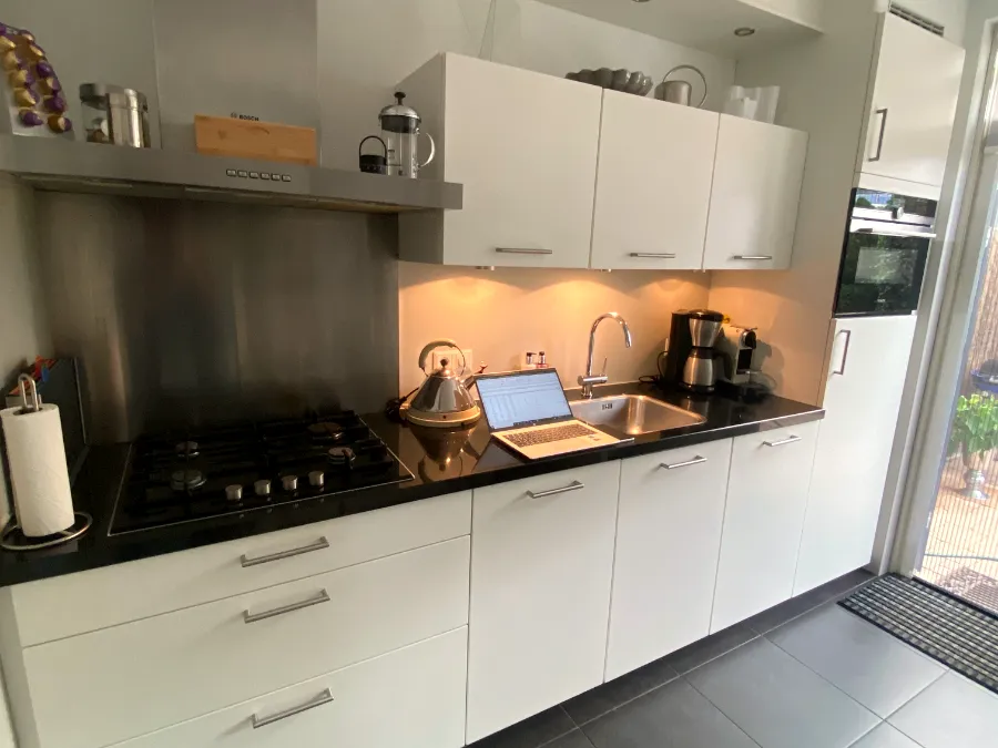 Witte keuken met zwart werkblad en verlichting onder de bovenkasten