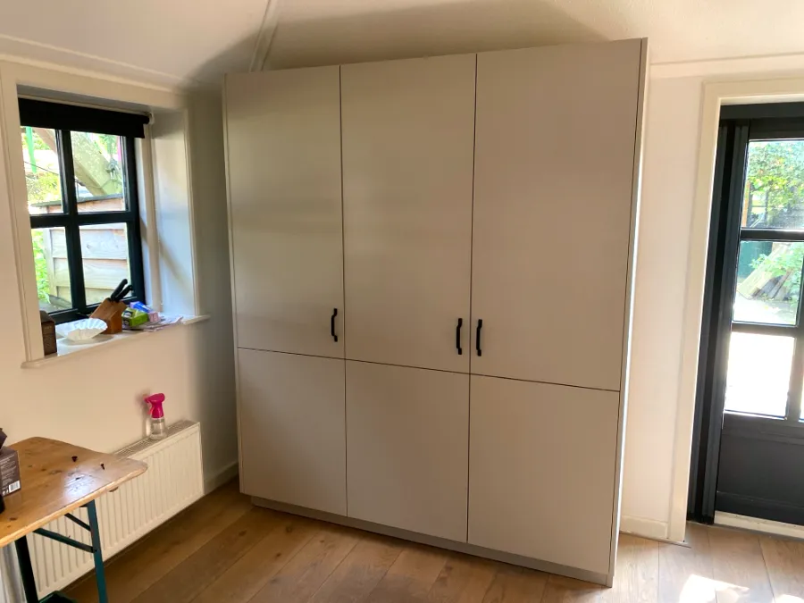 Hoge kastenwand in lichtgrijs met zwarte grepen