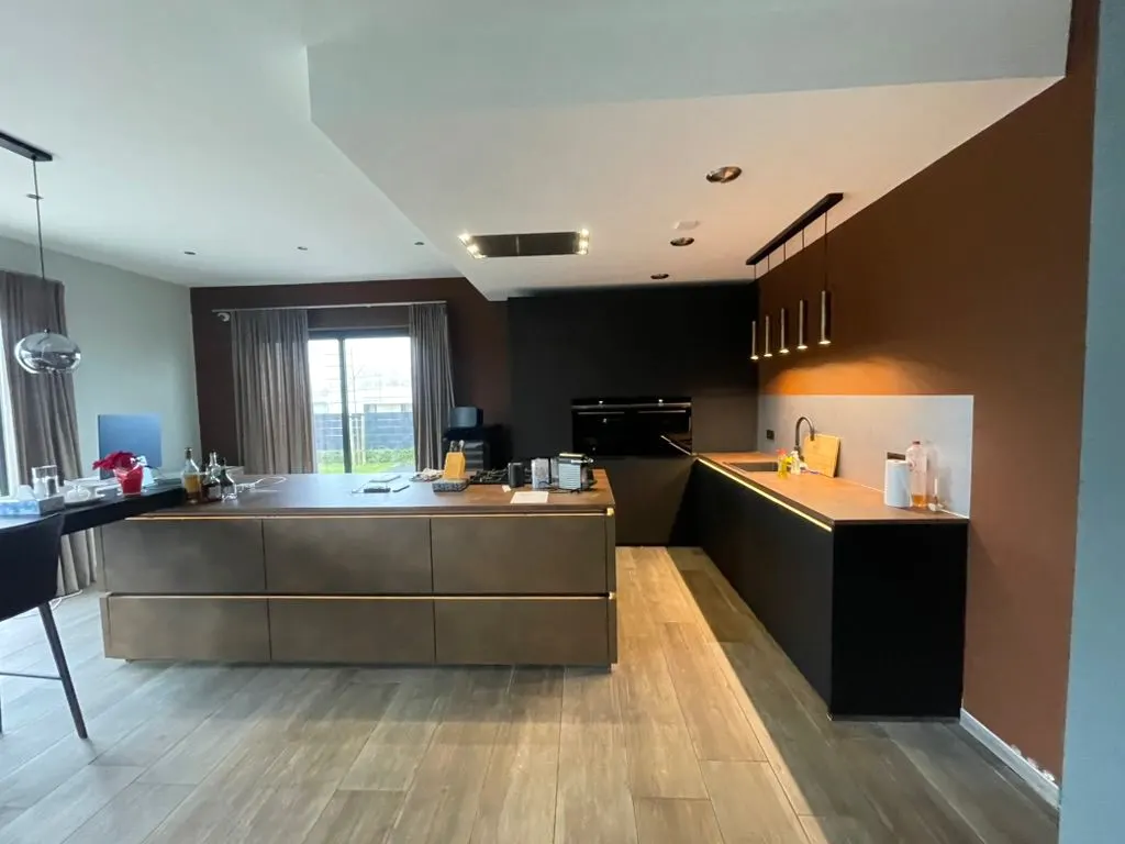 Kookeiland in bronslook voor een wand met zwarte hoge kasten