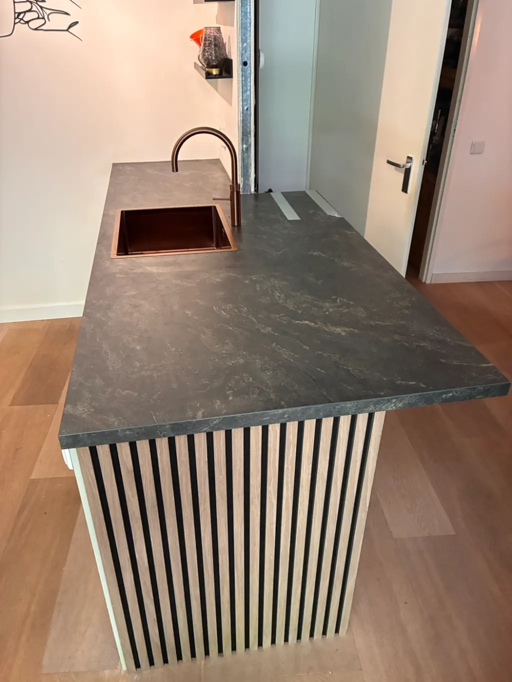 Eiland met houten lamellen, donker werkblad en koperen spoelbak