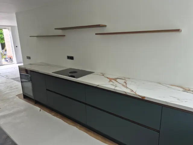 Lange keuken met donkergroene fronten en een marmerlook blad