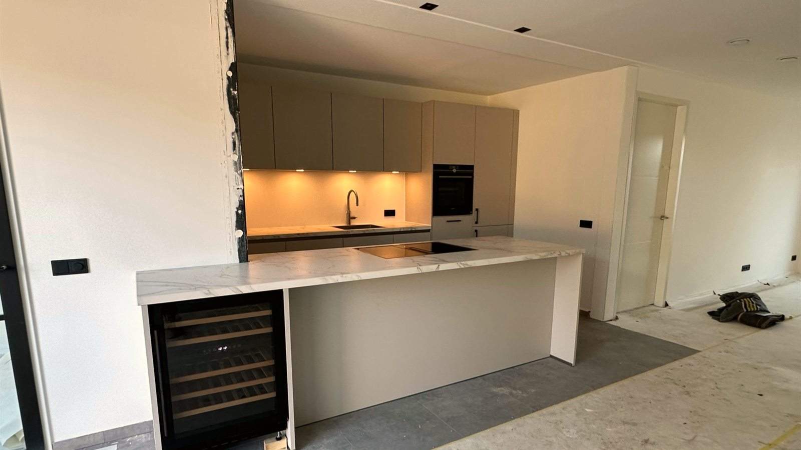 Lange kastenwand met wijnkoeler, huis nog in aanbouw
